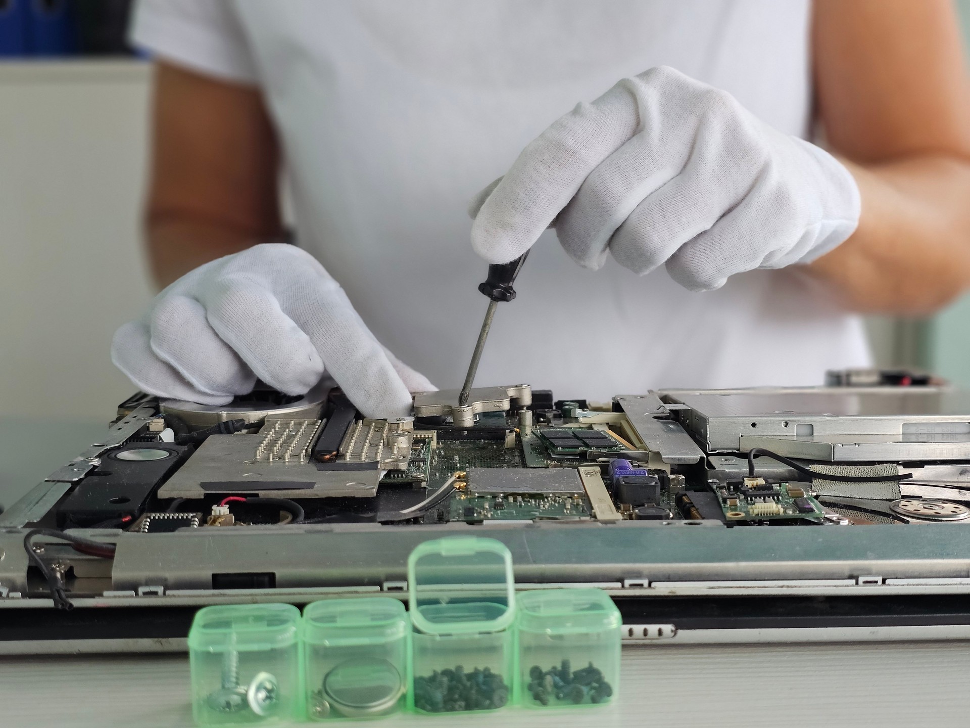 Technician repairs laptop motherboard using precision tools in a well-lit workspace concept